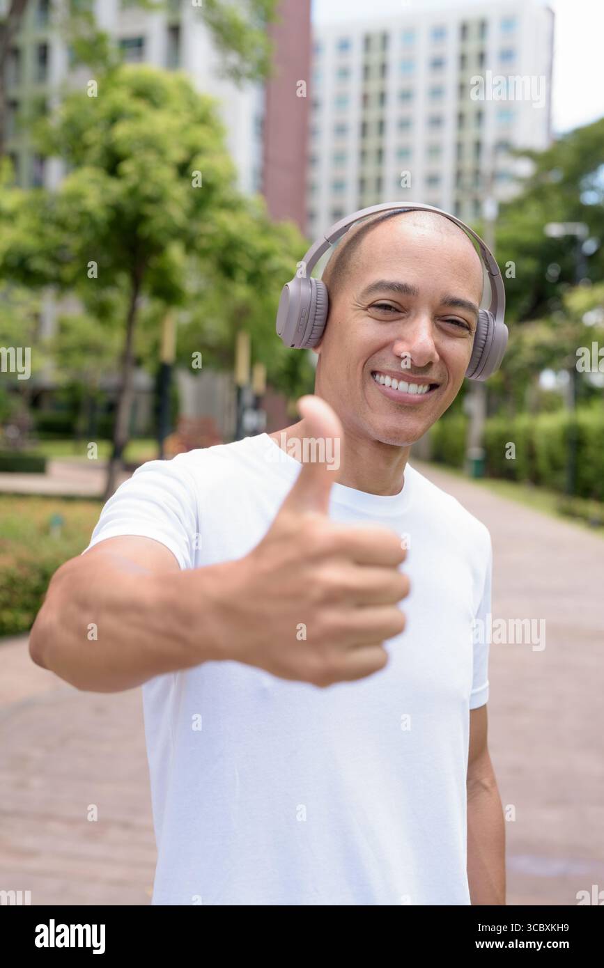 Glatze Latin man spaziert in der Stadt oder im Park und genießt die Bewegung im Freien. Fängt selbstbewussten Wellness-Lebensstil, aktive Gewohnheiten und gesunde Sommer Urban ein Stockfoto