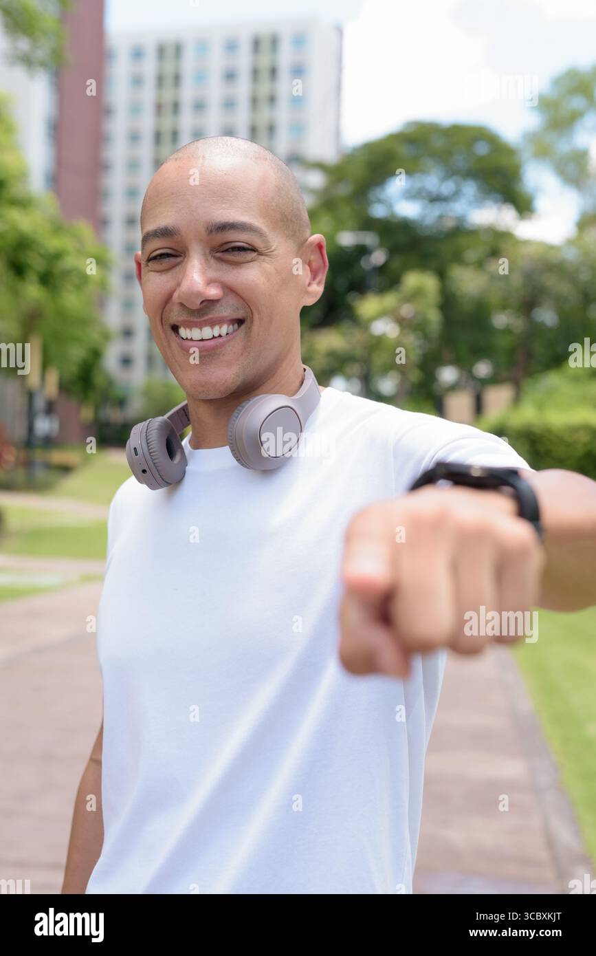 Glatze Latin man spaziert in der Stadt oder im Park und genießt die Bewegung im Freien. Fängt selbstbewussten Wellness-Lebensstil, aktive Gewohnheiten und gesunde Sommer Urban ein Stockfoto
