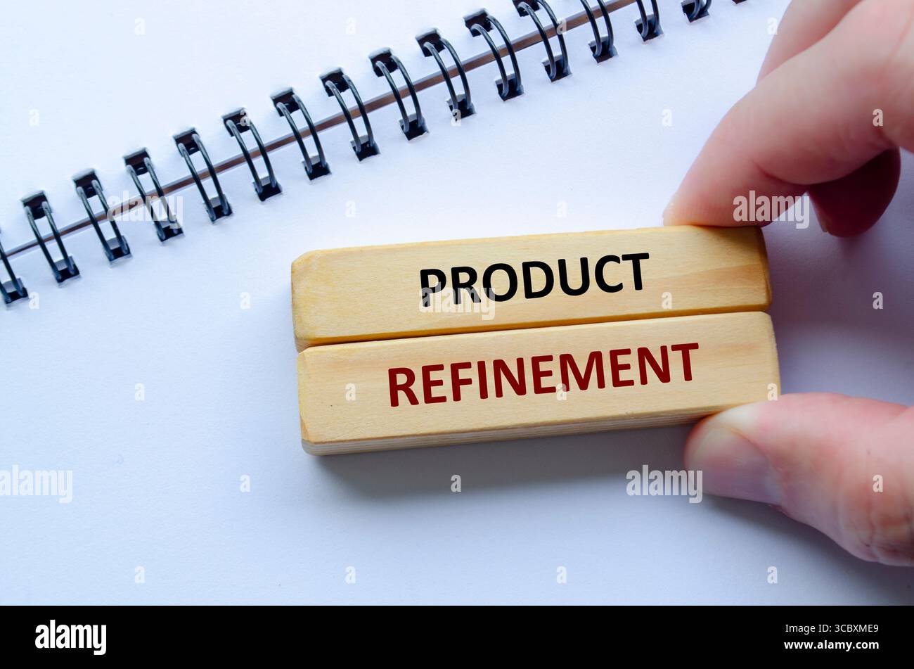 Text ZUR PRODUKTVERFEINERUNG auf Holzblöcken, Schwerpunkt auf kontinuierlicher Produktverfeinerung, um höchste Qualitäts- und Leistungsstandards zu erreichen. Stockfoto