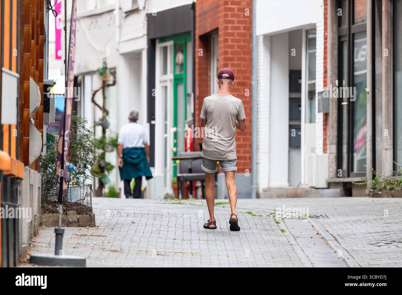 Mann, der eine steile Straße in der Altstadt von Braine L Alleud, Brabant Wallon, Belgien, wandert 14. Juli 2025 Stockfoto