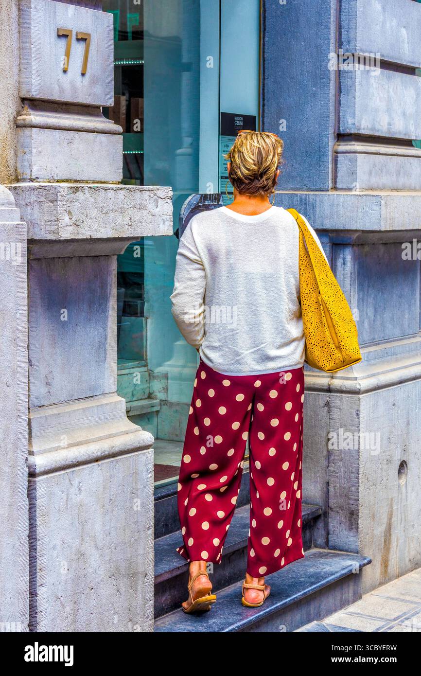 Rückansicht einer jungen Frau in Pünktchenhosen, die in der Tür steht - Brüssel, Belgioum. Stockfoto