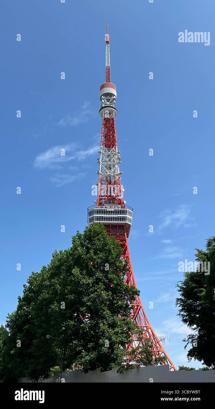 Nahaufnahme des ikonischen rot-weißen Tokio Tower vor einem klaren blauen Himmel mit verstreuten Wolken. Stockfoto