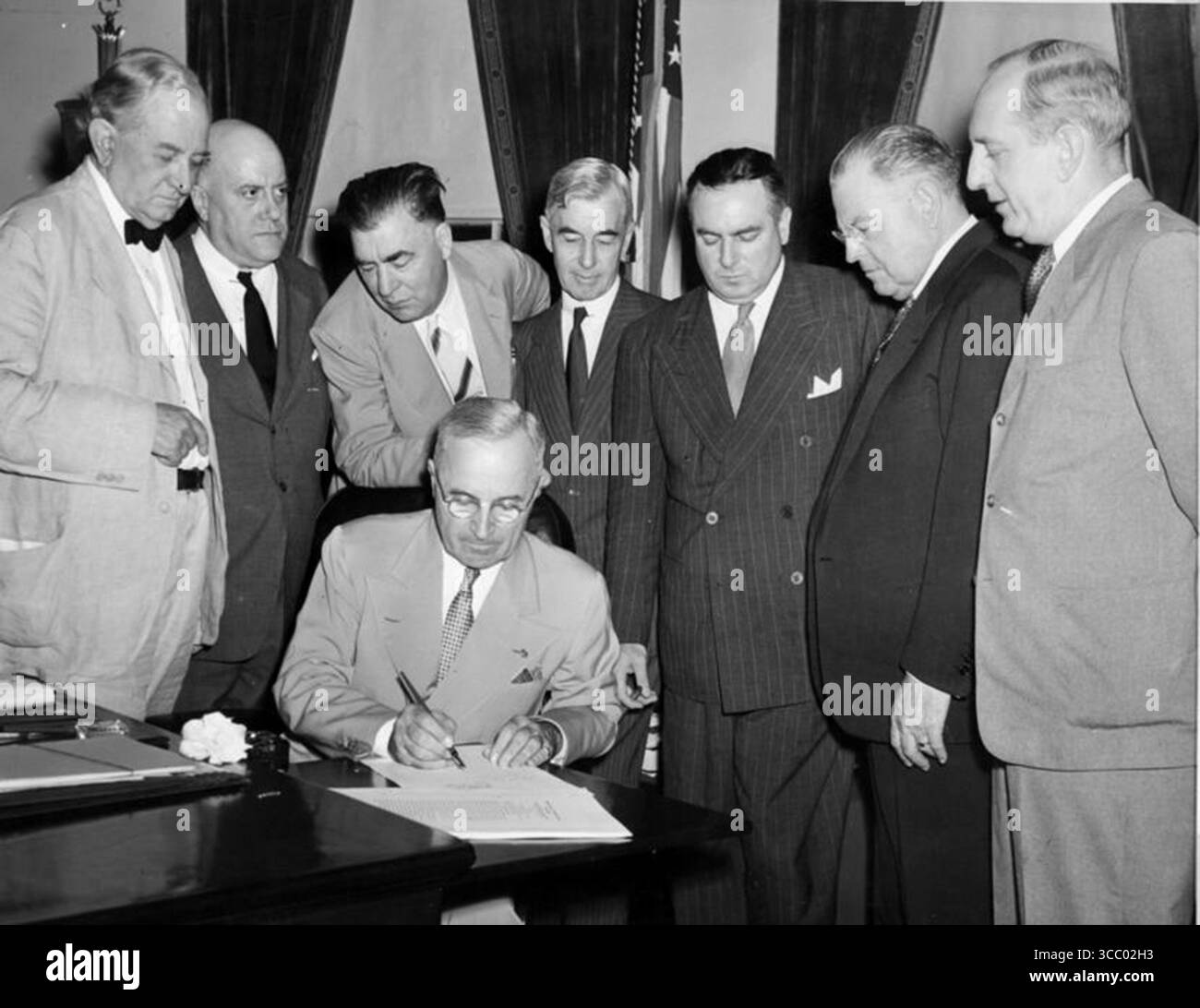 Präsident Harry S Truman unterzeichnet den Atomic Energy Act von 1946 zur Gründung der US Atomic Energy Commission. Hinter dem Präsidenten, von links nach rechts: Die Senatoren Tom Connally, Eugene D. Millikin, Edwin C. Johnson, Thomas C. Hart, Brien McMahon, Warren R. Austin und Richard B. Russell. Stockfoto