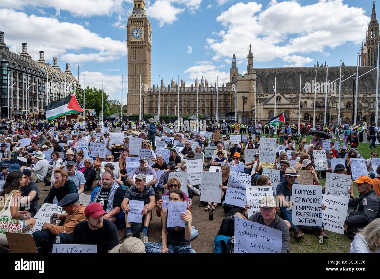 Ein Massenprotest vor dem Parlament in London. Demonstranten mit Plakaten „Ich bin gegen Völkermord, ich unterstütze palästinensische Aktionen“, während sie darauf warten, verhaftet zu werden. Stockfoto