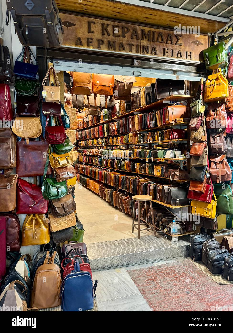 Traditionelles Lederwarengeschäft im Herzen von Athen, Griechenland, mit farbenfrohen handgefertigten Taschen und Accessoires. - Smartphone-aufgenommenes Stockfoto