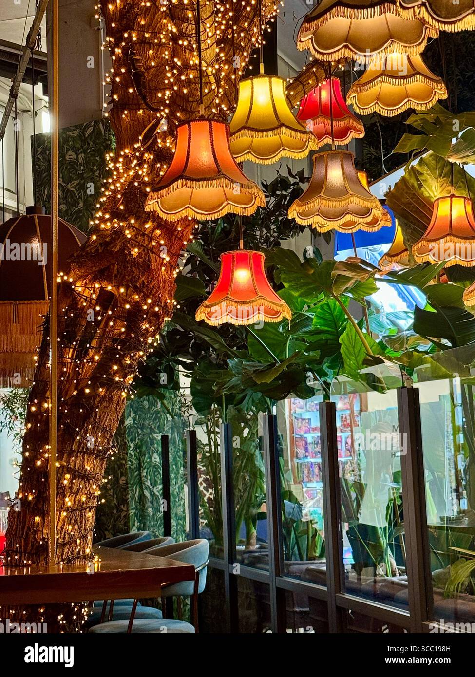 Restaurant-Dekoration im Freien mit Vintage-Lampen und Feenlichtern, die um einen Baum in Athen gewickelt sind Stockfoto