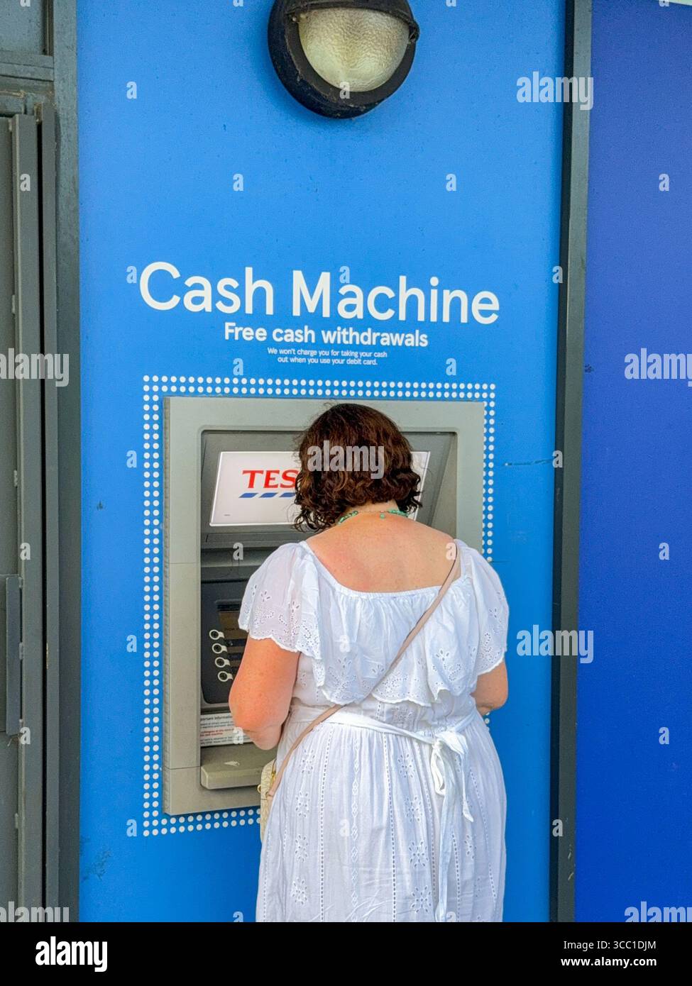 Pontypridd, Wales, Vereinigtes Königreich - 12. Juli 2025: Person, die Geld an einem Geldautomaten außerhalb der Filiale von Tesco Express im Stadtzentrum von Pontypridd abhebt - Smartphone-aufgenommenes Stockfoto