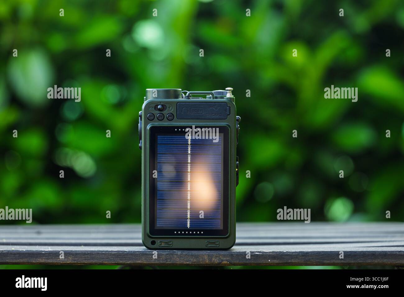 VINKOVCI, KROATIEN, 06.13.2025: Ein tragbares Außenradio mit eingebautem Solarmodul sitzt auf einer Holzoberfläche mit verschwommenem grünen Hintergrund, illust Stockfoto