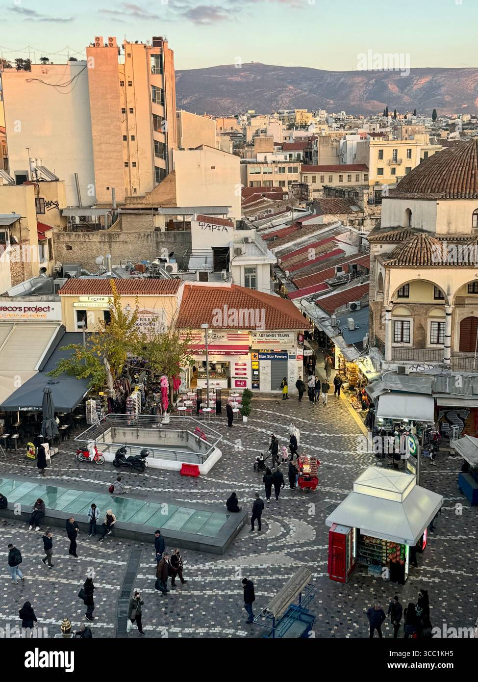 Golden-Hour-Blick auf den Monastiraki Plaza in Athen, Griechenland, mit lebendiger urbaner Atmosphäre und historischer Architektur. - Smartphone-aufgenommenes Stockfoto