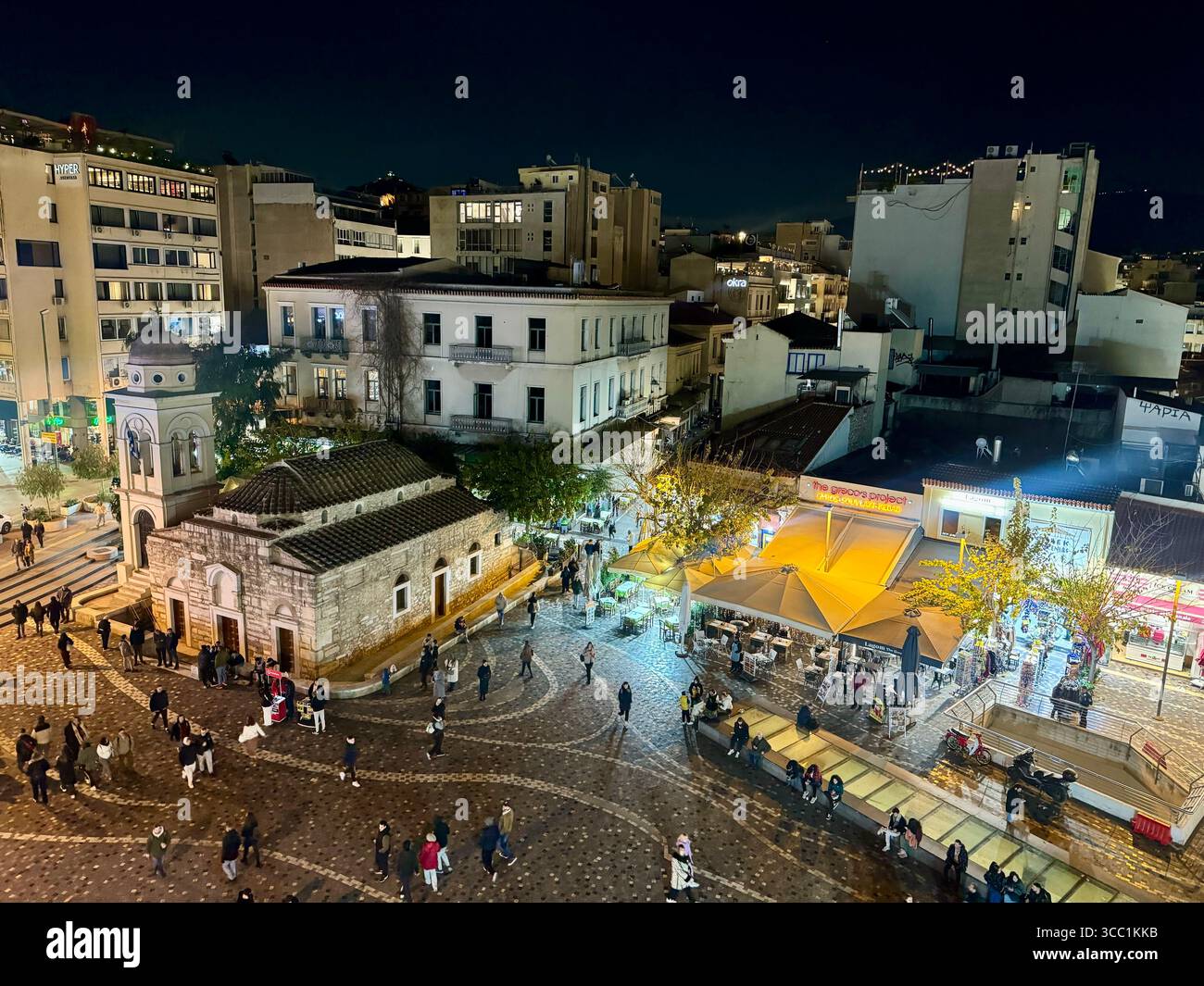 Nächtlicher Blick auf den Monastiraki-Platz in Athen, Griechenland, mit einer alten Kirche, beleuchteten Straßen und Spaziergängen. Stockfoto
