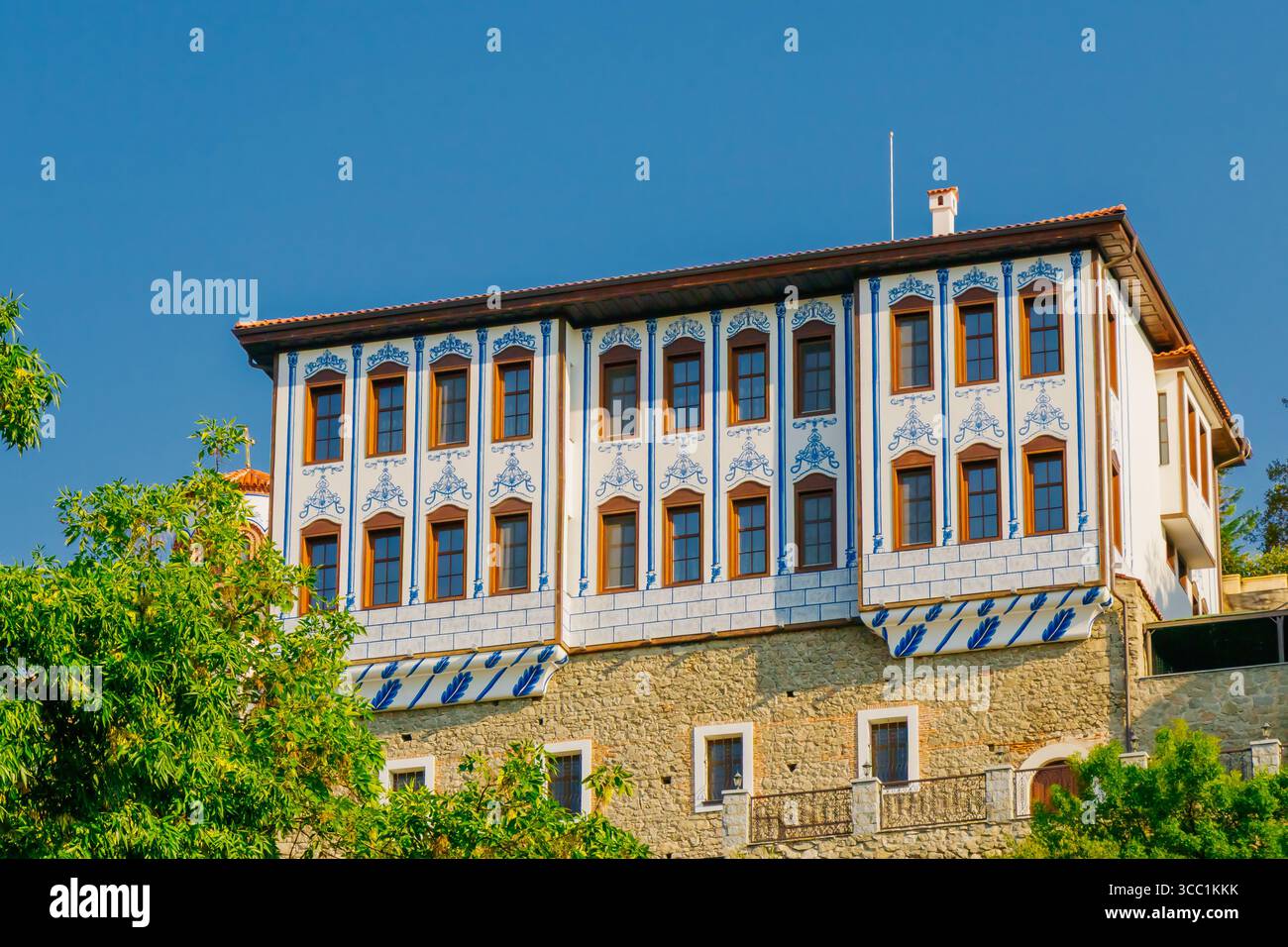 Ein historisches Gebäude mit komplexen Blau- und Weißmustern steht unter klarem Himmel, umgeben von üppigem Grün, das den Architekten hervorhebt Stockfoto