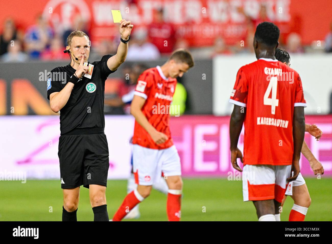 Kaiserslautern, Deutschland. August 2025. Fußball: Bundesliga 2, 1. FC Kaiserslautern - FC Schalke 04, Spieltag 2, Fritz-Walter-Stadion. Maxwell Gyamfi (1. FC Kaiserslautern) wird von Schiedsrichter Martin Petersen eine gelbe Karte gezeigt. Hinweis: Uwe Anspach/dpa - WICHTIGER HINWEIS: Gemäß den Vorschriften der DFL Deutschen Fußball-Liga und des DFB Deutschen Fußball-Bundes ist es verboten, im Stadion und/oder des Spiels aufgenommene Fotografien in Form von sequenziellen Bildern und/oder videoähnlichen Fotoserien zu verwenden oder zu verwenden./dpa/Alamy Live News Stockfoto