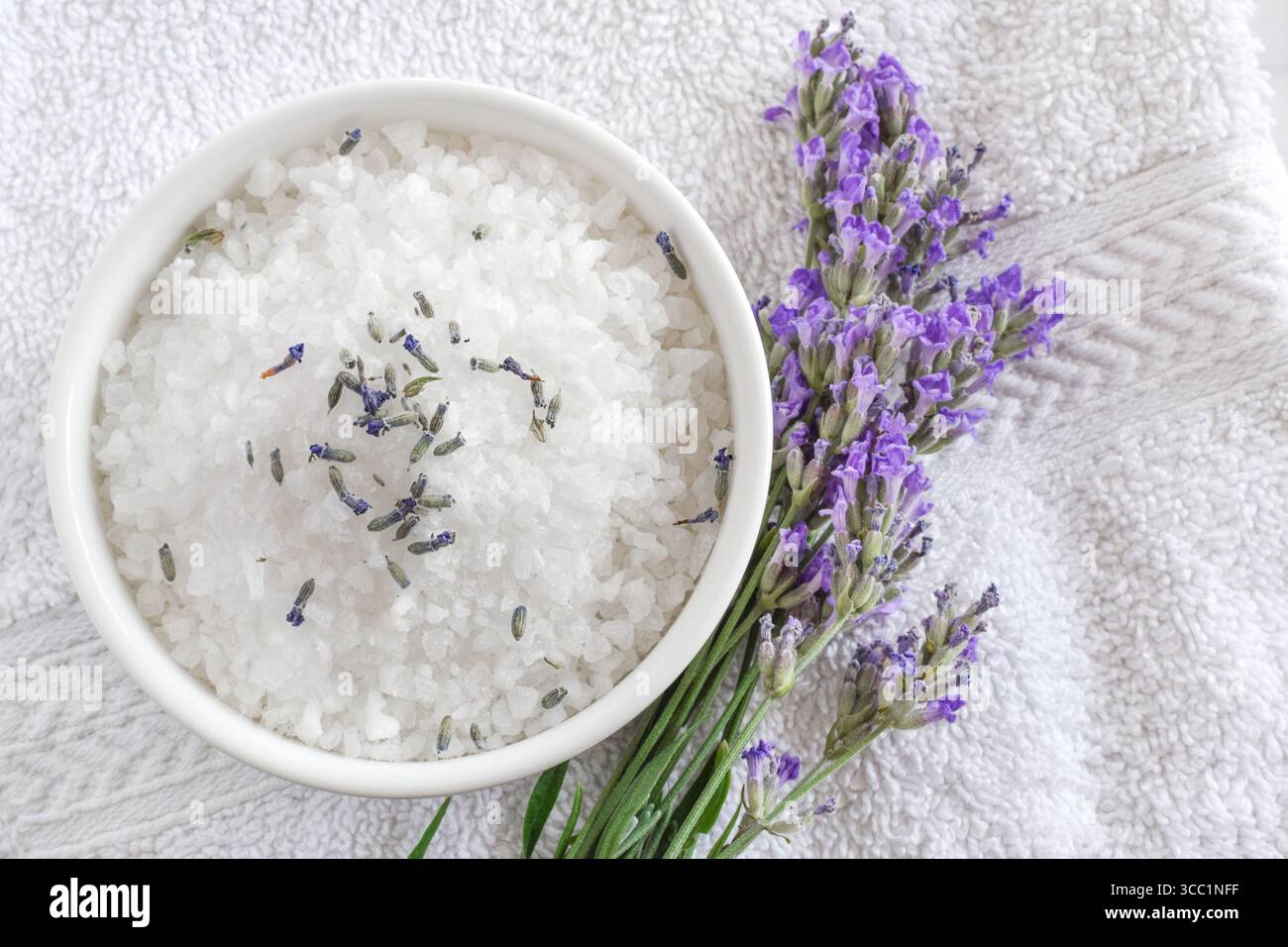Badesalz mit Lavendelblüten auf weißem Handtuch Stockfoto