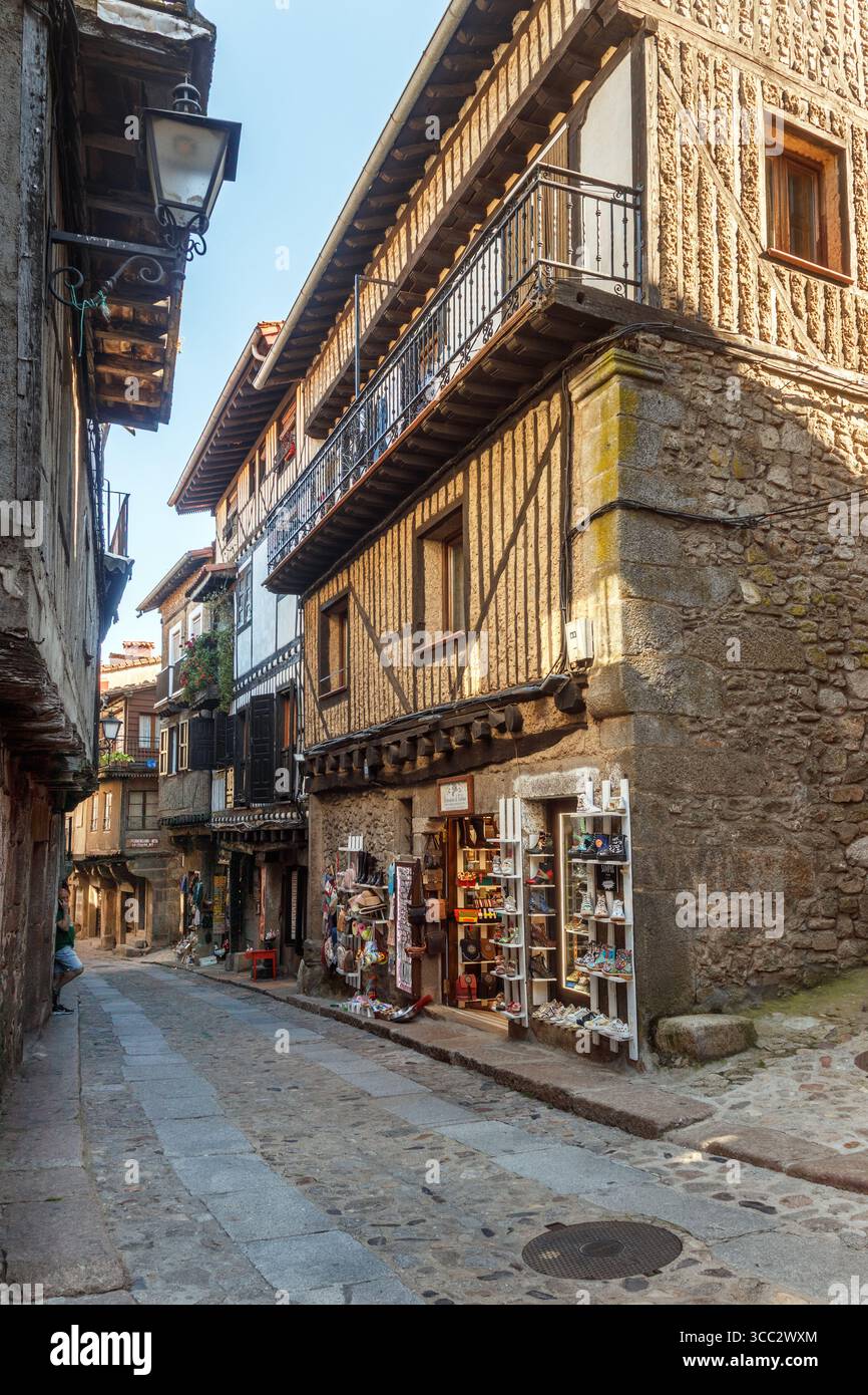La Alberca, Spanien . 5-31-2024: Kopfsteinpflasterstraße gesäumt von alten Häusern und Geschäften im Dorf La Alberca in der Provinz Salamanca in Spanien. Stockfoto