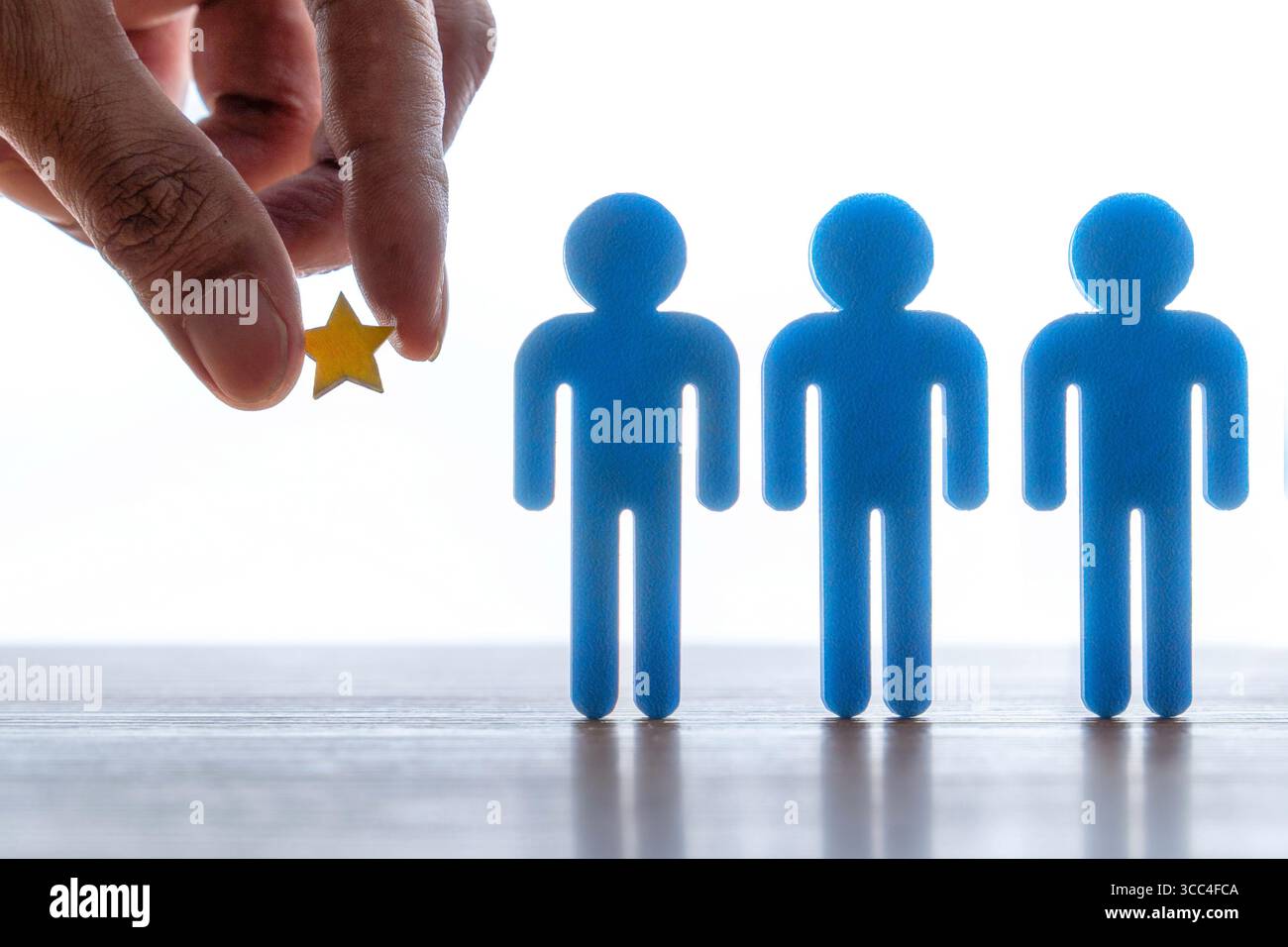 Hand hält einen Stern neben einem Team. Konzept für Auszeichnung, Wertschätzung und Belohnung für Mitarbeiter. Stockfoto