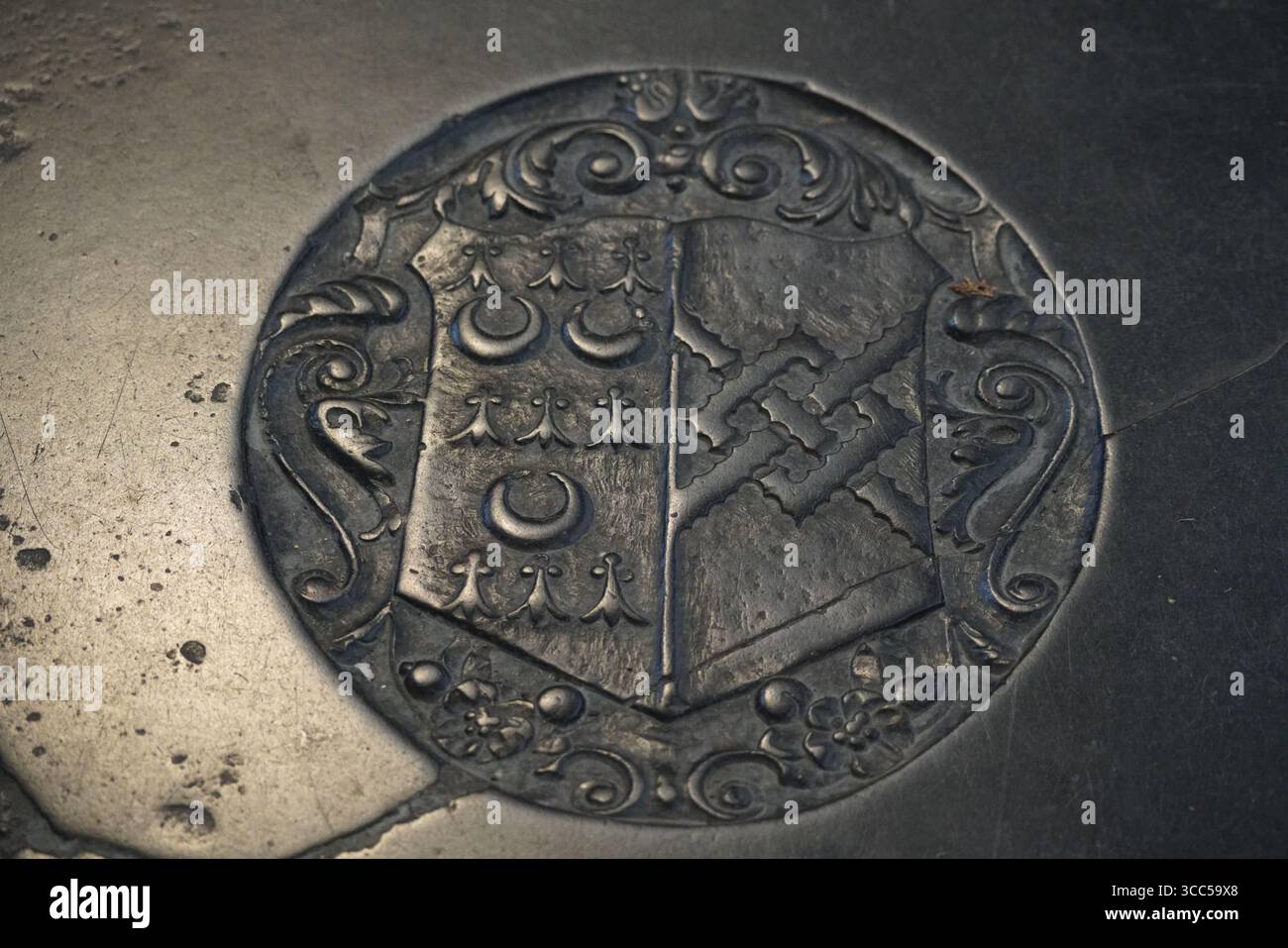 Graviertes Metallic-Wappen mit komplizierten Mustern auf einer Steinoberfläche. Salisbury, England Stockfoto