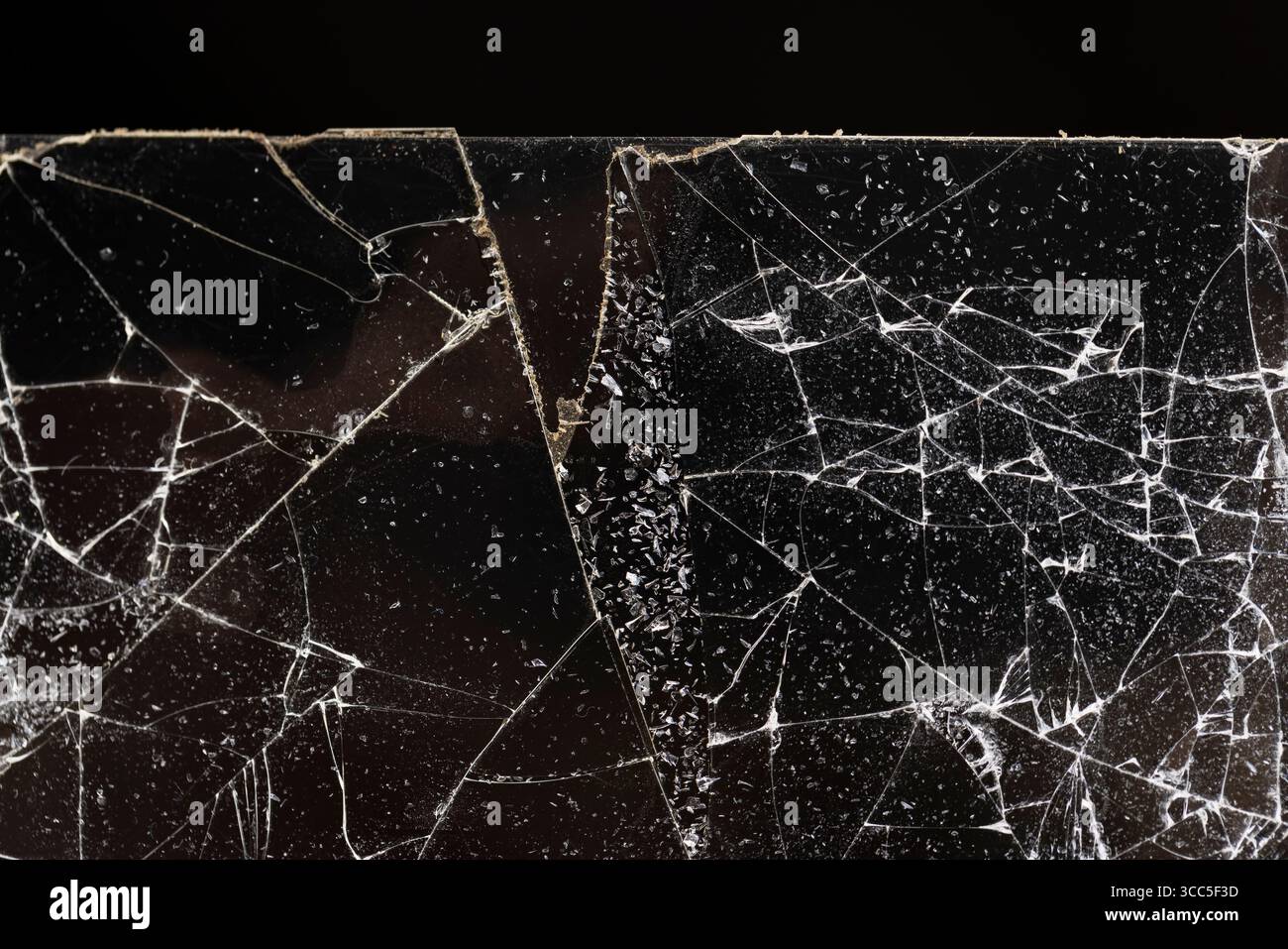 Zerbrochen mit vielen Schäden und Glasstücken auf schwarzem Hintergrund, dünnes Glas in viele Stücke gebrochen, Nahaufnahme Stockfoto