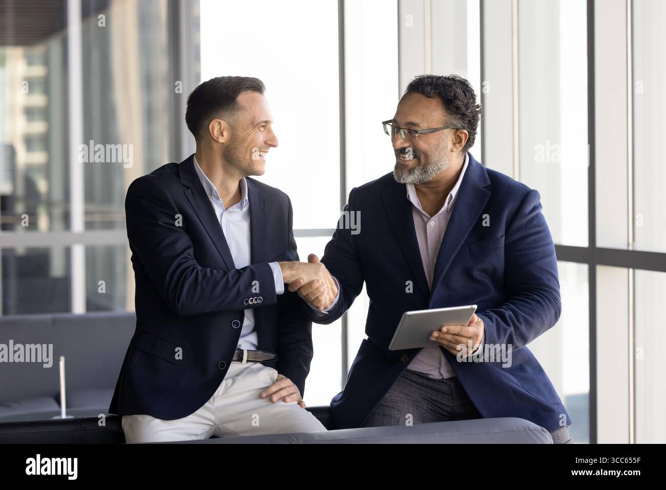 Glückliche multiethnische jüngere und ältere Geschäftspartner schütteln die Hand Stockfoto