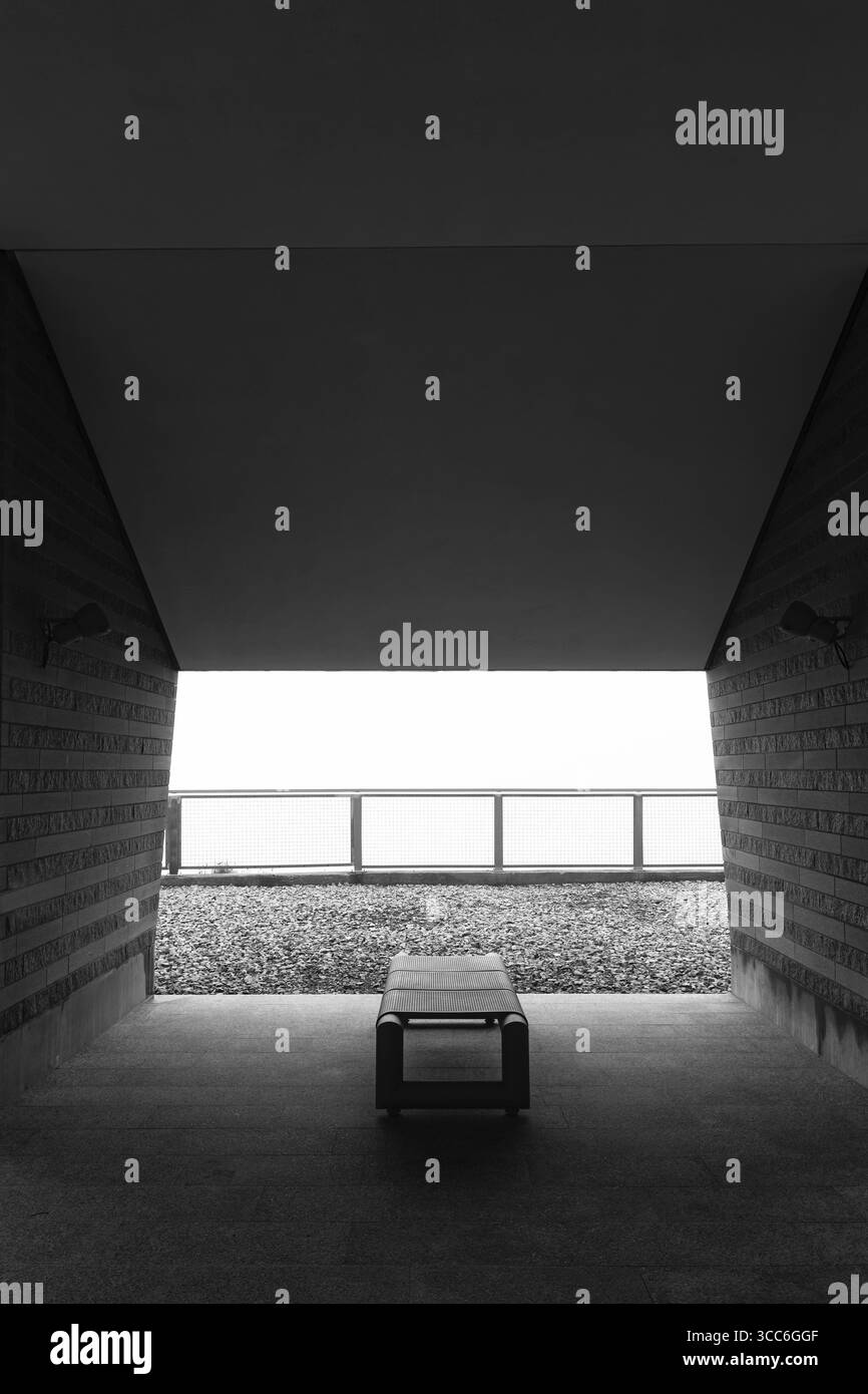 Modernes Gebäude mit Bank und Sonnenlicht an einem bewölkten Tag in Monte Generoso, Tessin, Schweiz Stockfoto