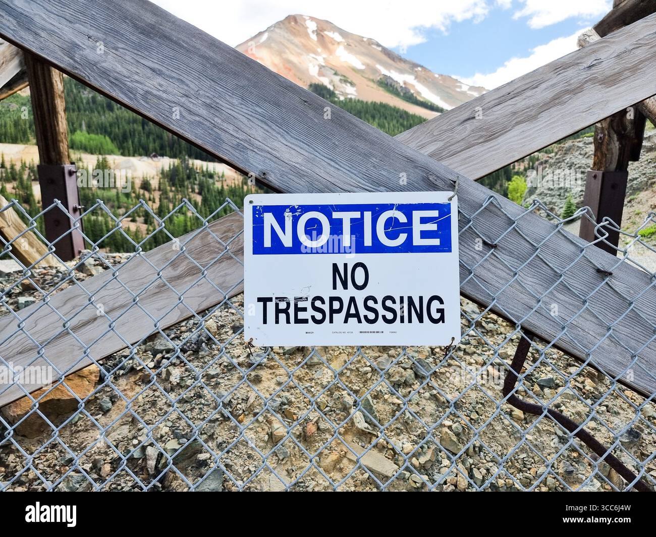 Weißes und blaues Schild mit TEXTANMERKUNG - KEIN BETRETEN eines Zauns; Berg im Hintergrund Stockfoto