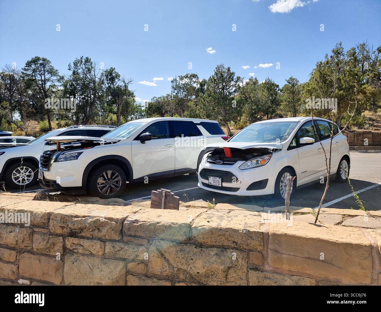 Weiße Fahrzeuge mit leicht geöffneter Motorhaube (Motorhaube, Motorhaube, Motorhaube) zur Kühlung des Motors usw. ohne Sommerwärme nach langer oder intensiver Fahrt - Smartphone-aufgenommenes Stockfoto