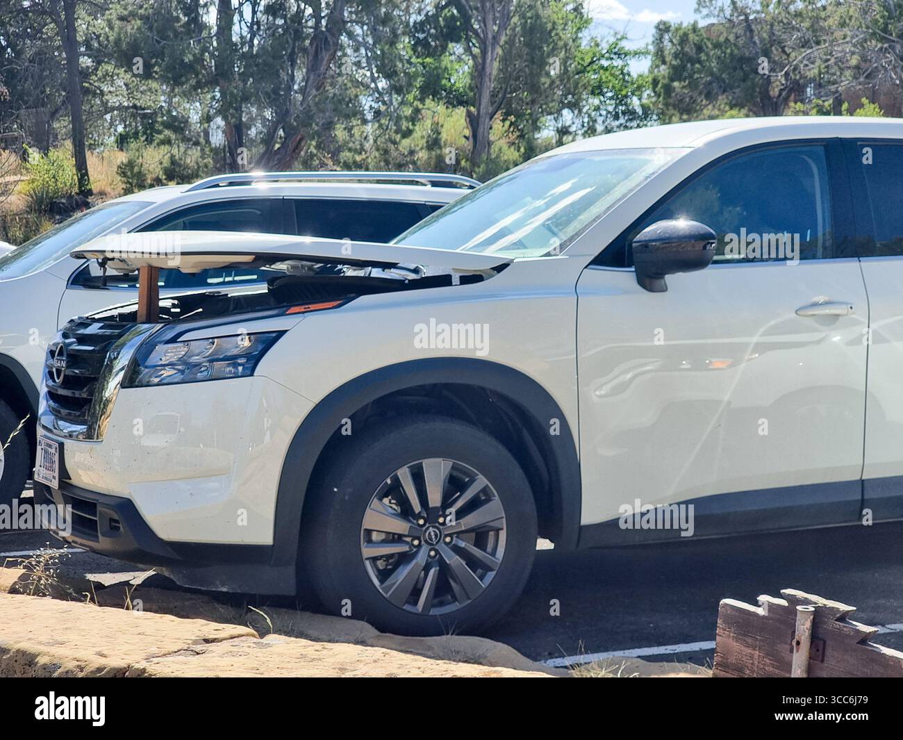 Weiße Fahrzeuge mit leicht geöffneter Motorhaube (Motorhaube, Motorhaube, Motorhaube) zur Kühlung des Motors usw. ohne Sommerwärme nach langer oder intensiver Fahrt - Smartphone-aufgenommenes Stockfoto
