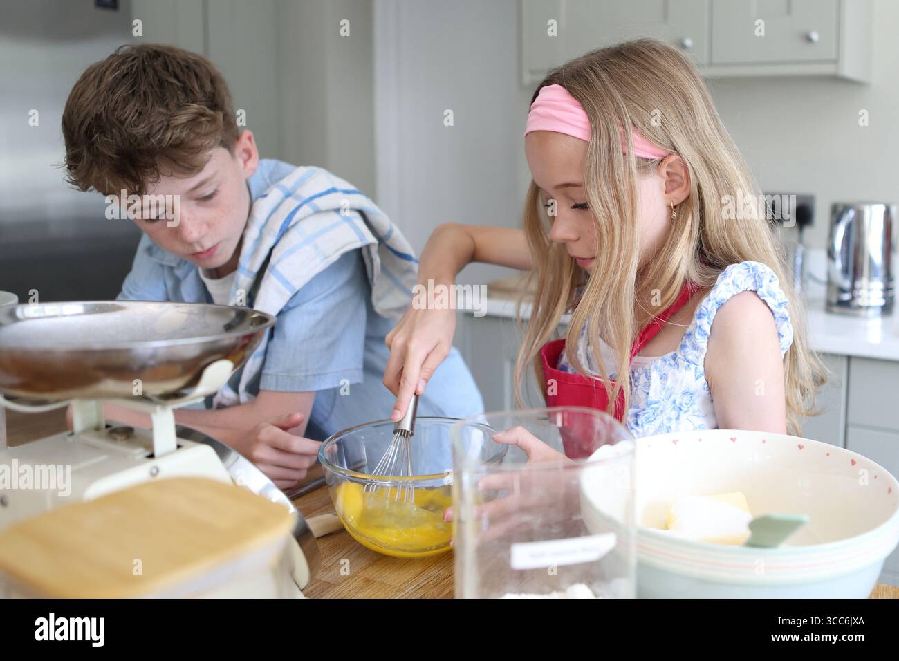 Mädchen, das Eier zum Backen von Kuchen in der Küchenschüssel mit dem Handrührer verquirlt Stockfoto
