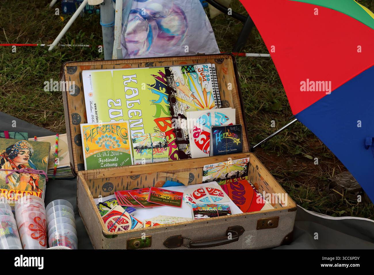 HERZBERG FESTIVAL 2025 - 24.07.2025, Breitenbach am Herzberg, Deutschland, Deutschland - das Herzberg Festival feiert in diesem Jahr seinen 55. Geburtstag unter dem Motto BERG VOLLER LIEBE C ãBerg voller LiebeÒ - wie in den vielen Jahren zuvor trifft sich hier die Hippie-Szene vom 24. bis 27. Juli in der Nähe der osthessischen Gemeinde Breitenbach am Herzberg, um auf der großen Festivalwiese Musik zu hören, zu tanzen und ausgelassen zu feiern. Zahlreiche Traktoren und Lkws mit ihren großen Wassertanks versorgt die Festival-Gemeinde. Angebot von Herzbergkalendern, Herzberg-Bechern und Herzberg-Fly Stockfoto