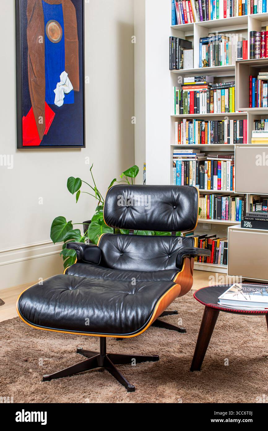 Ein Eames Lounge Chair mit poliertem schwarzem Leder, das in einem modernen Wohnzimmerkontext gestaltet ist. Stockfoto