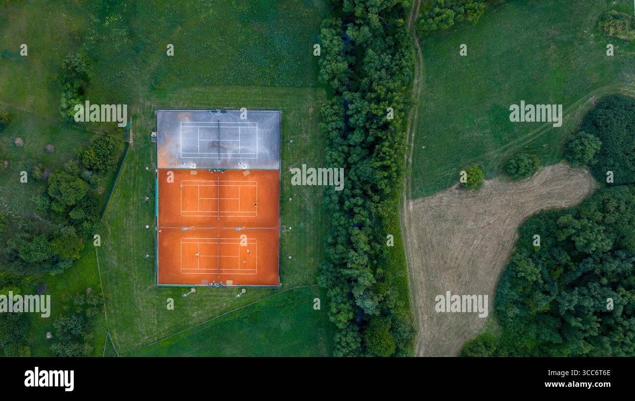 Top-Down-Drohnenfoto von Tennisplätzen im Freien mit natürlicher Landschaft und Waldrand in der Nähe Stockfoto