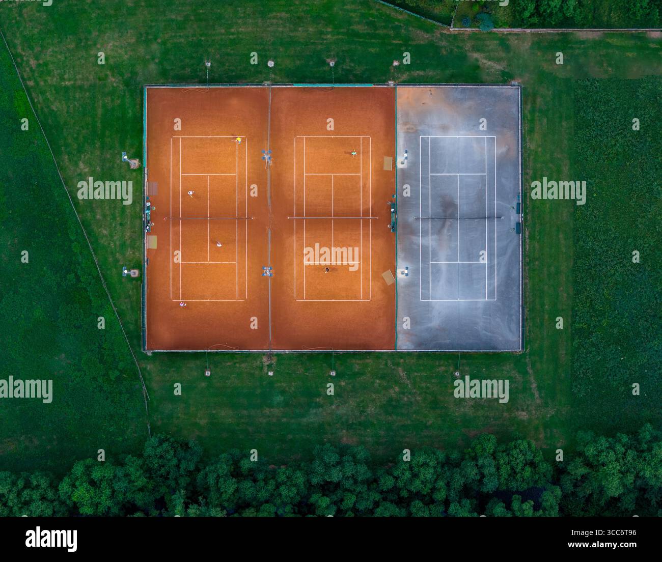 Top-Down-Tennisplatz-Bild mit dynamischen Spielmomenten in üppiger Landschaft Stockfoto