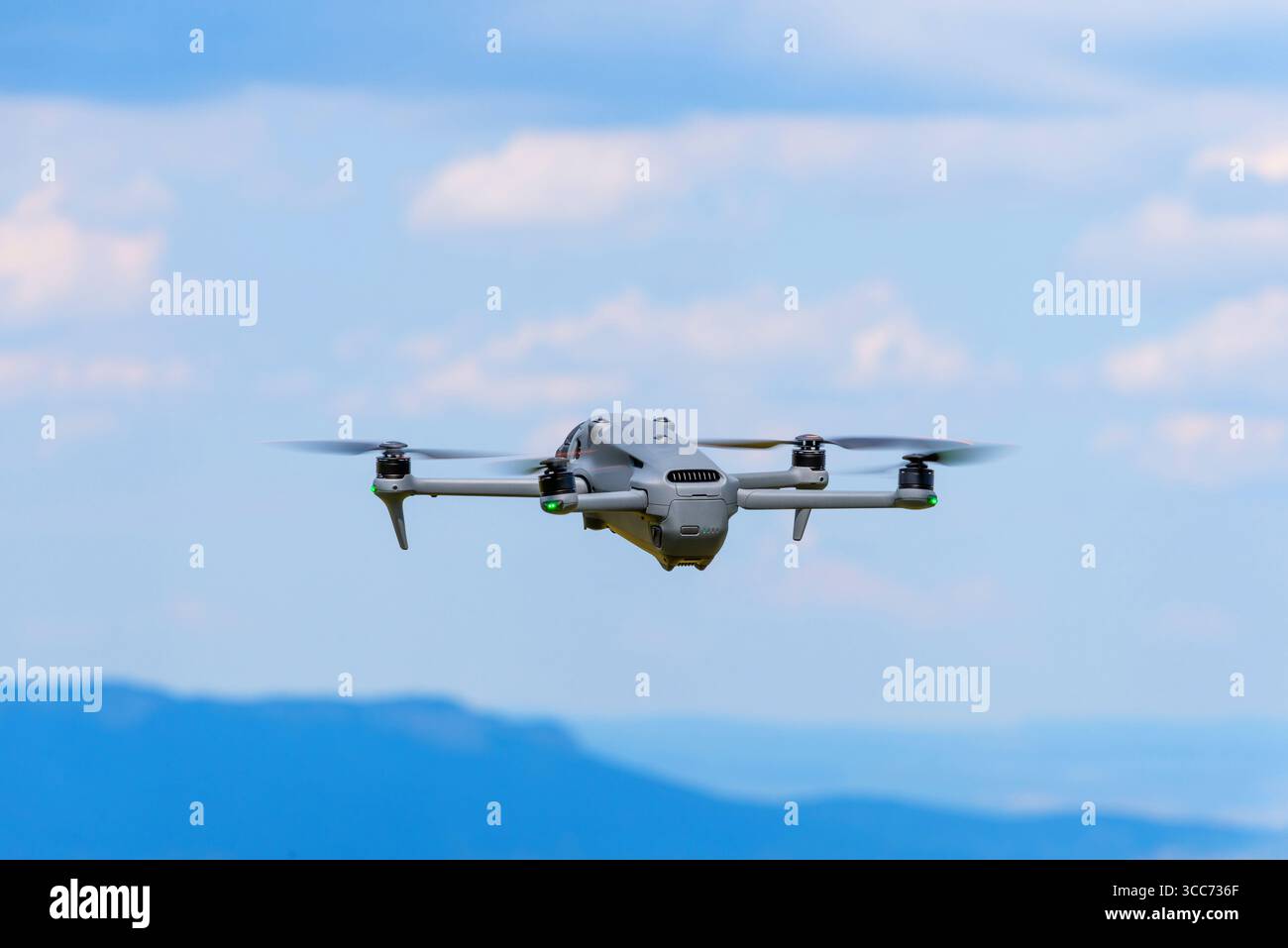 Drohne fliegt über Berge unter blauem Himmel mit Wolken Stockfoto