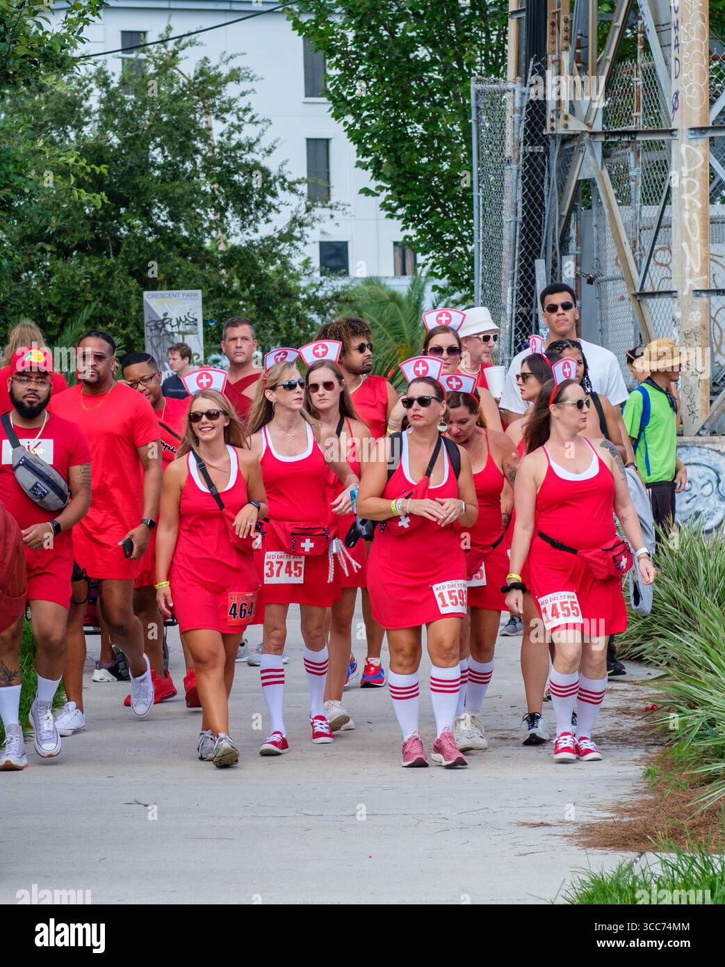 New Orleans, LA, USA – 13. August 2022: Männer und Frauen in roten Kleidern gehen in Kostümen zum Beginn des jährlichen Red Dress Run in Marigny Stockfoto