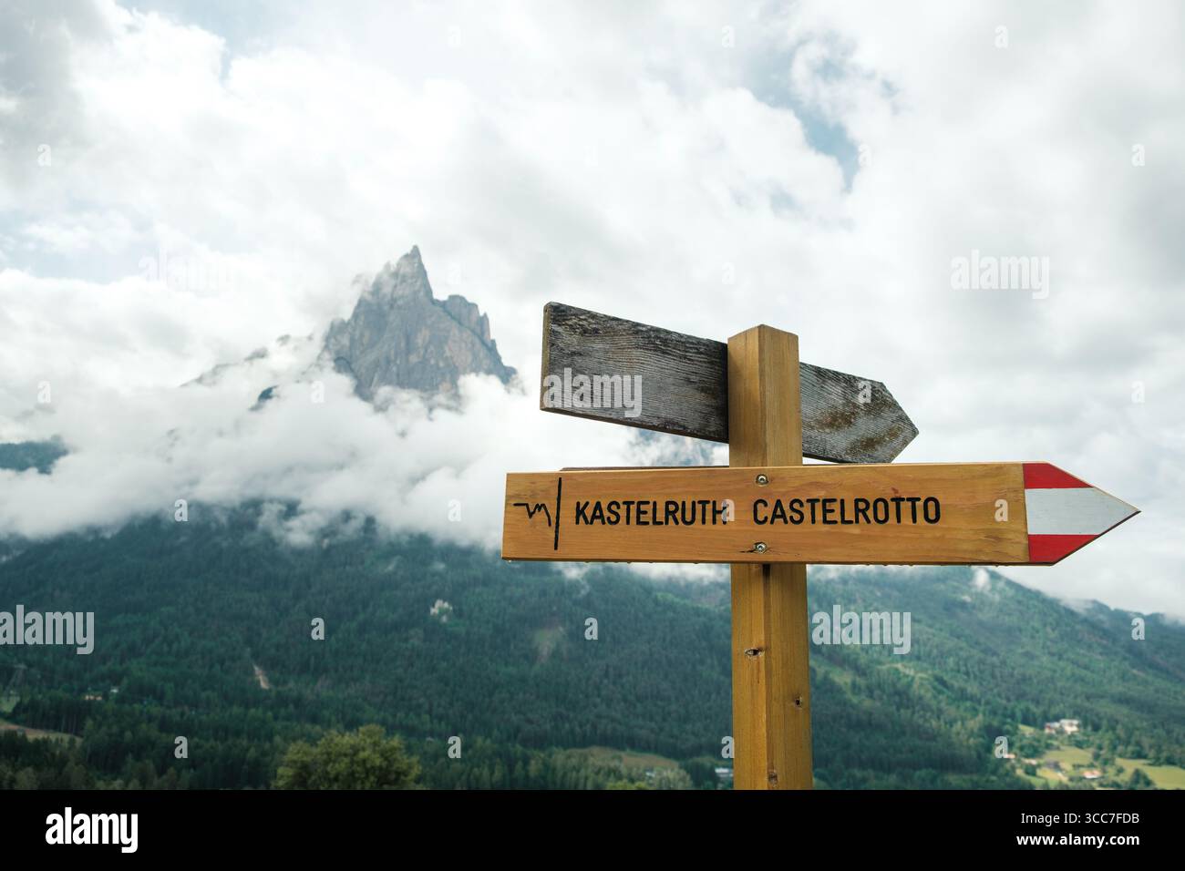 Kastelruth, Südtirol, Italien - 01.07.2024: Blick auf das Richtungsschild des Wanderweges in die Stadt Kastelruth mit dem Schlern im Ba Stockfoto