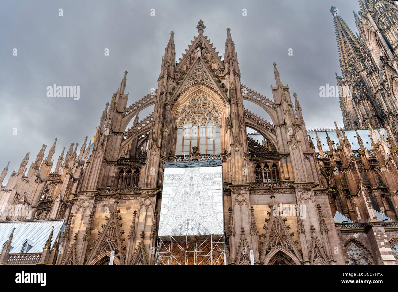 Köln, Deutschland - 15. Juni 2025: Kunstvolle Fassade des Kölner Doms mit aufwändigen Steinarbeiten und großen Buntglasfenstern unter einem stimmungsvollen, o Stockfoto