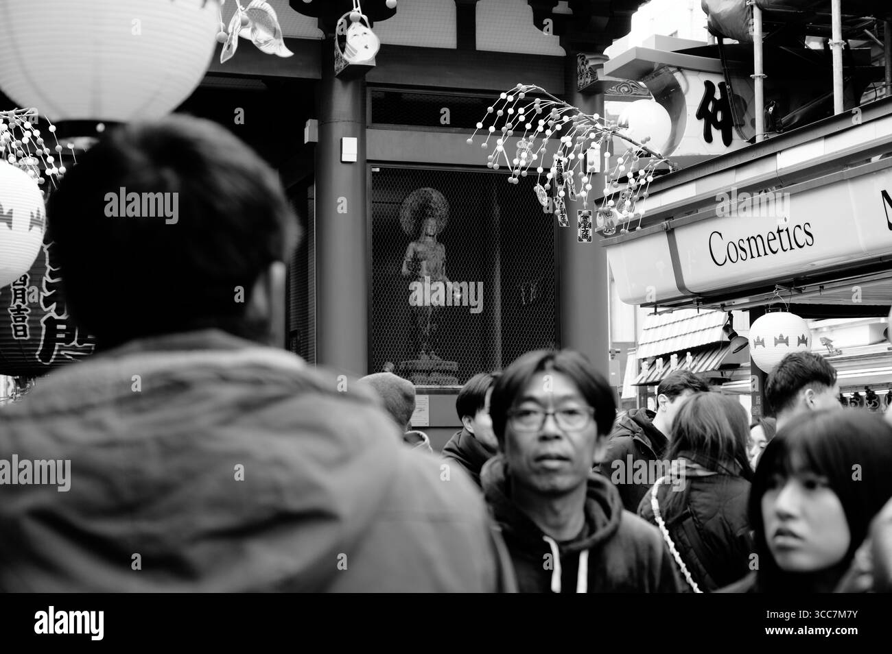 Die Menschenmassen passieren eine buddhistische Statue am Kaminarimon-Tor des Sensō-JI-Tempels in Asakusa Stockfoto