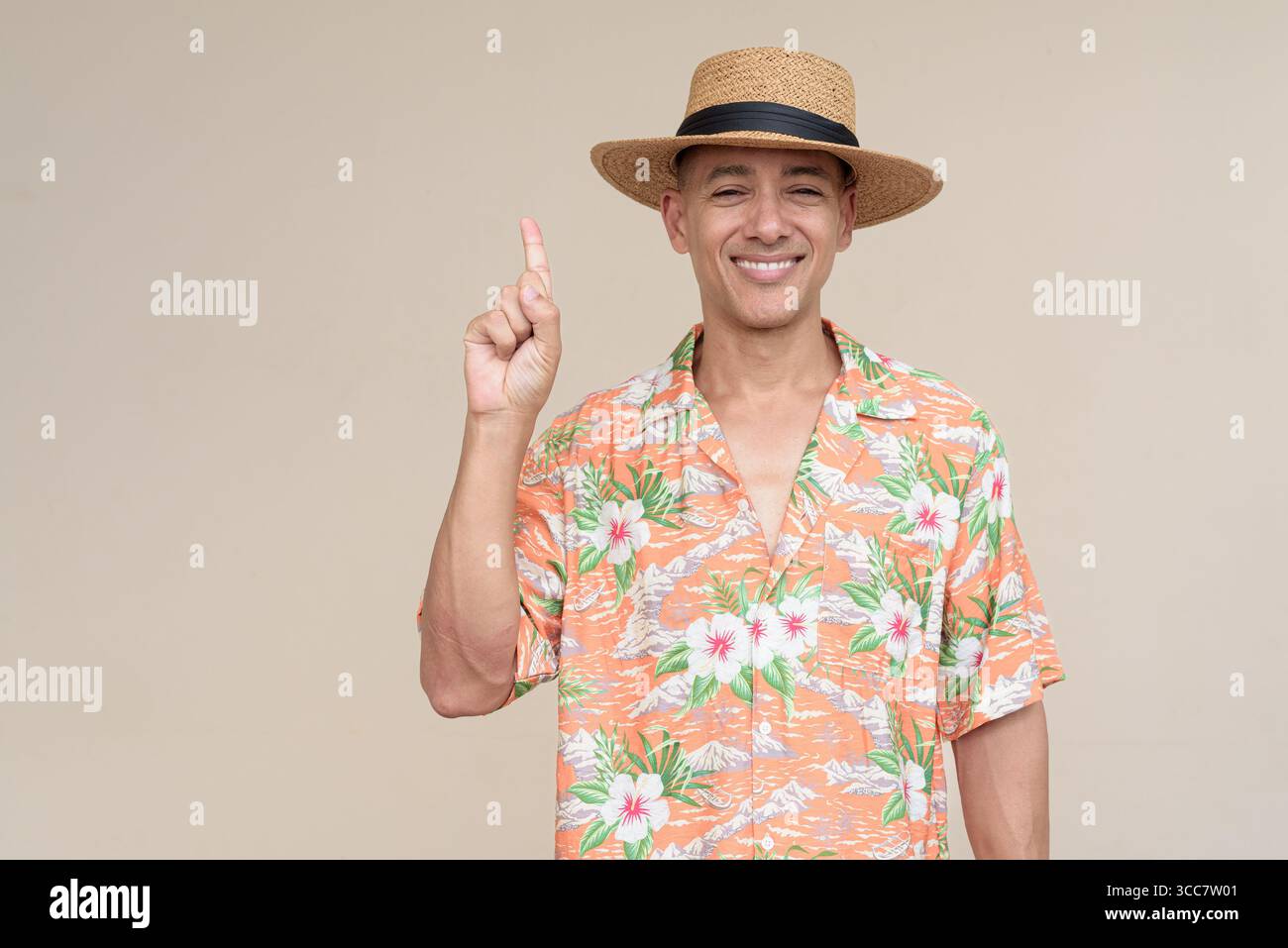 Glücklicher hispanischer Mann mit Panamahut und tropischem hawaiianischem Hemd, gekleidet in legere Sommermode. Der fröhliche Tourist posiert in entspanntem Urlaub Stockfoto