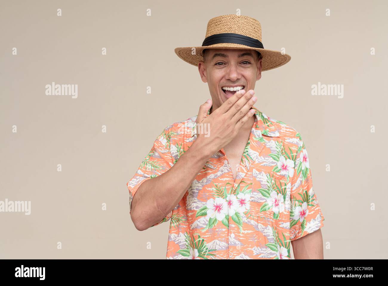 Glücklicher hispanischer Mann mit Panamahut und tropischem hawaiianischem Hemd, gekleidet in legere Sommermode. Der fröhliche Tourist posiert in entspanntem Urlaub Stockfoto