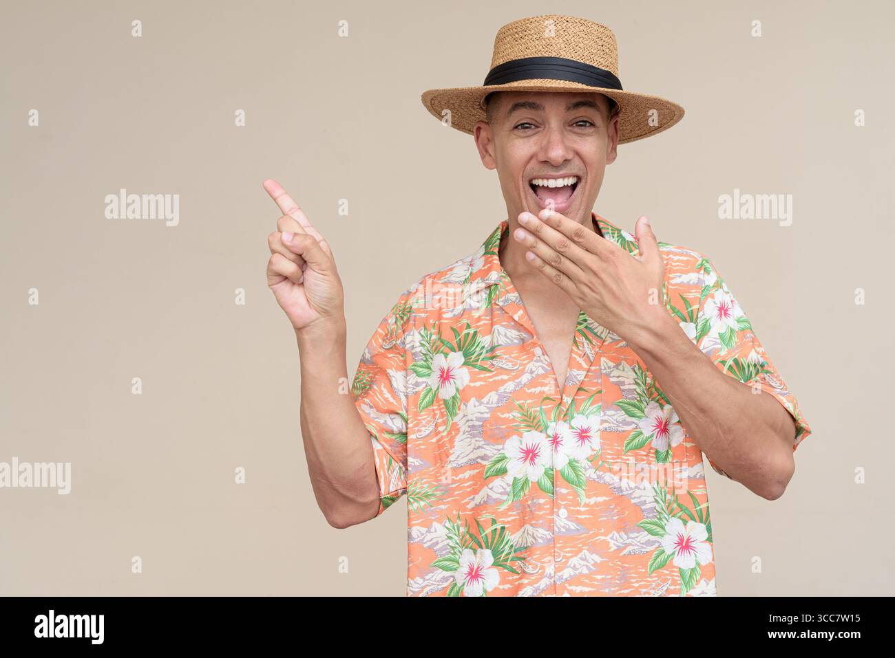 Glücklicher hispanischer Mann mit Panamahut und tropischem hawaiianischem Hemd, gekleidet in legere Sommermode. Der fröhliche Tourist posiert in entspanntem Urlaub Stockfoto