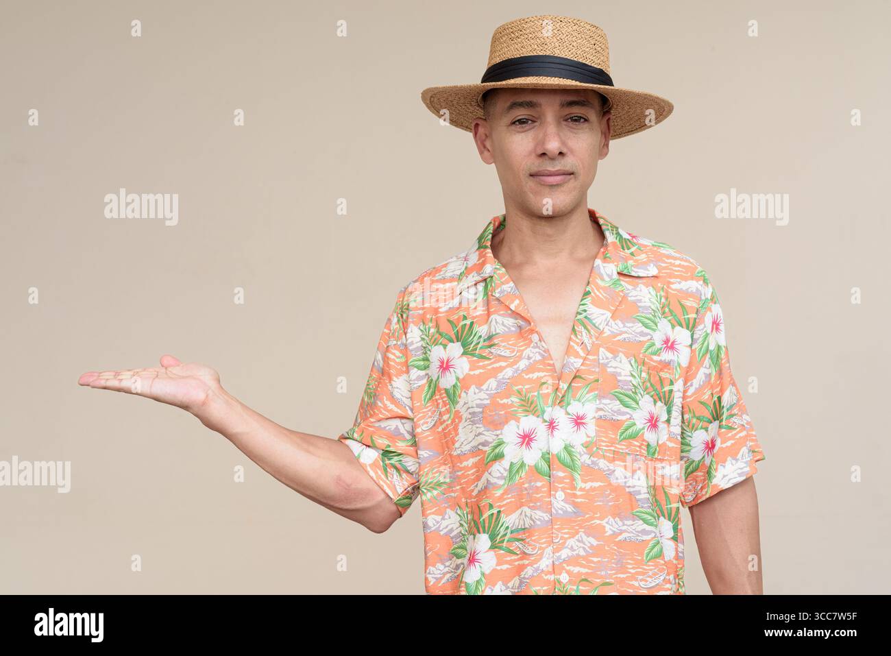 Glücklicher hispanischer Mann mit Panamahut und tropischem hawaiianischem Hemd, gekleidet in legere Sommermode. Der fröhliche Tourist posiert in entspanntem Urlaub Stockfoto