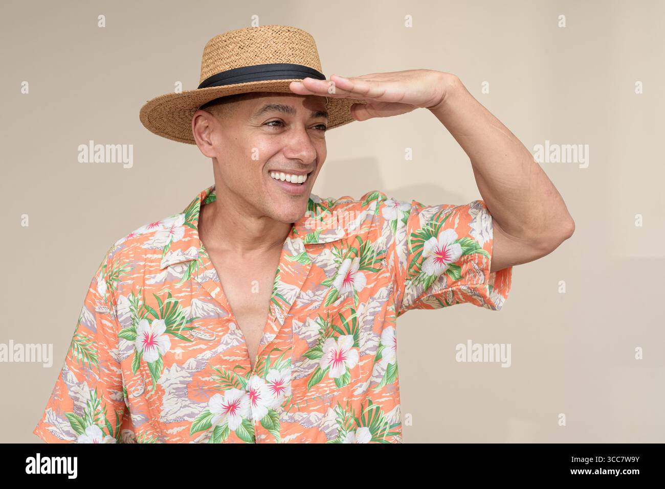 Glücklicher hispanischer Mann mit Panamahut und tropischem hawaiianischem Hemd, gekleidet in legere Sommermode. Der fröhliche Tourist posiert in entspanntem Urlaub Stockfoto