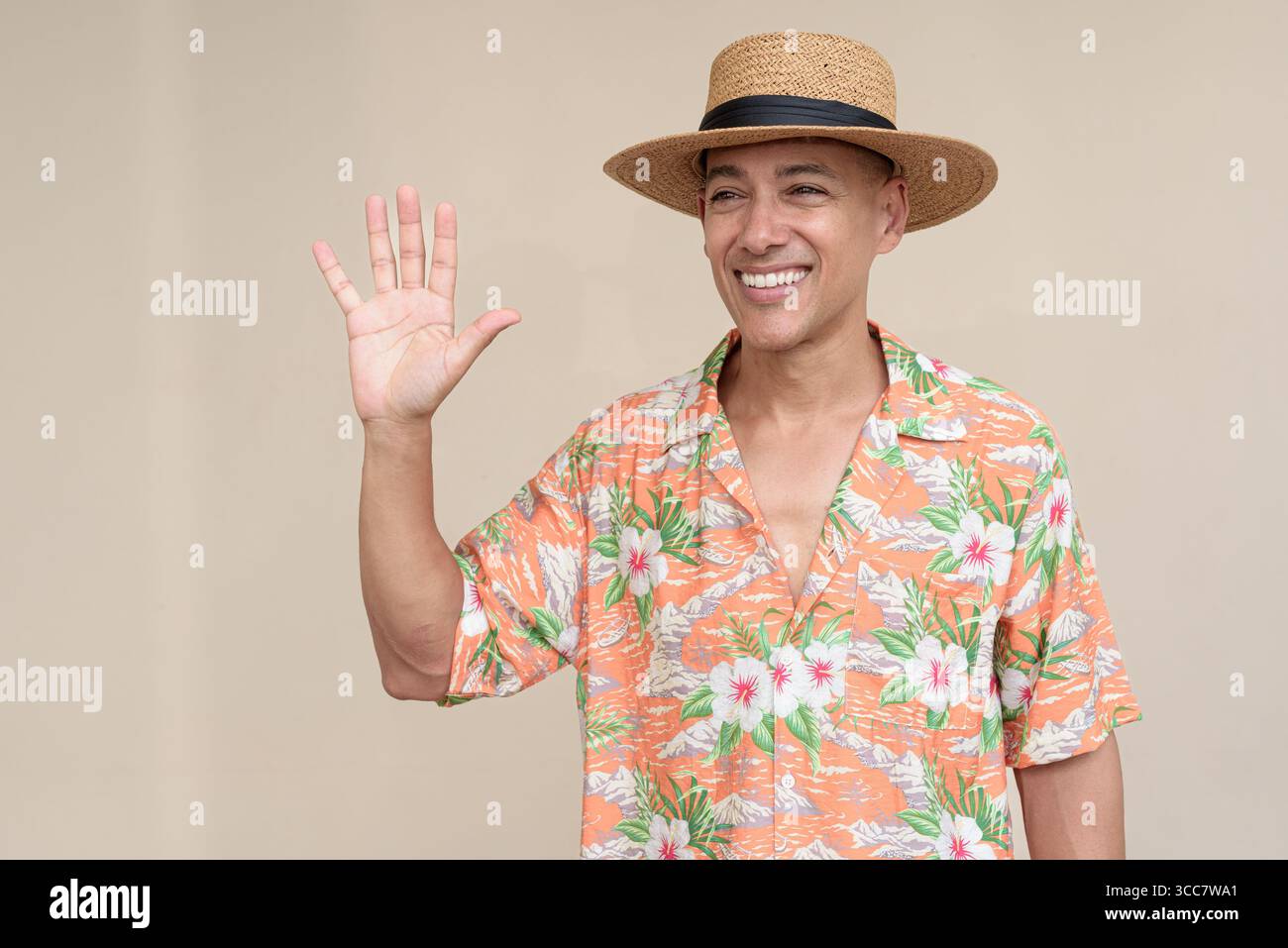 Glücklicher hispanischer Mann mit Panamahut und tropischem hawaiianischem Hemd, gekleidet in legere Sommermode. Der fröhliche Tourist posiert in entspanntem Urlaub Stockfoto