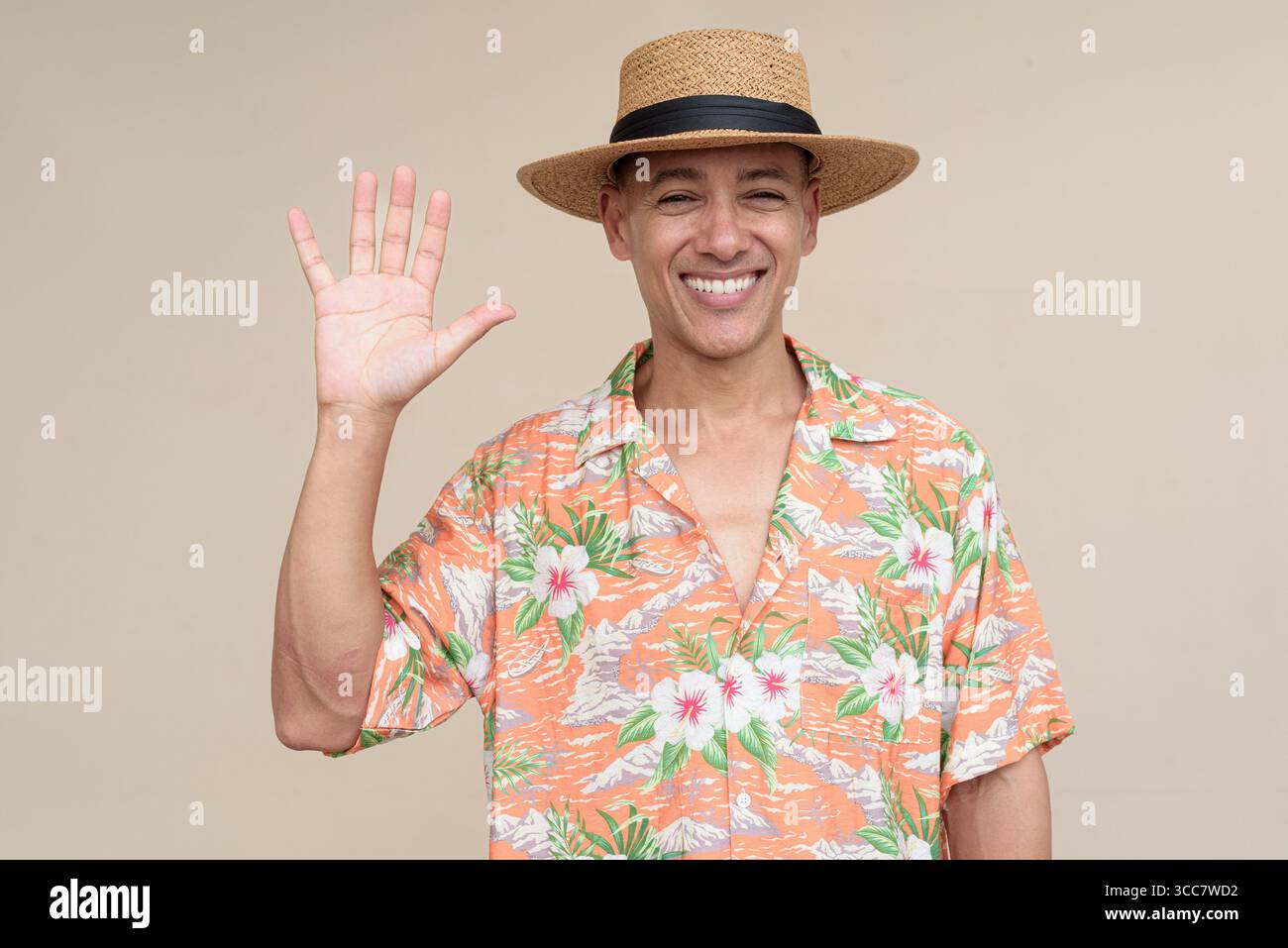 Glücklicher hispanischer Mann mit Panamahut und tropischem hawaiianischem Hemd, gekleidet in legere Sommermode. Der fröhliche Tourist posiert in entspanntem Urlaub Stockfoto