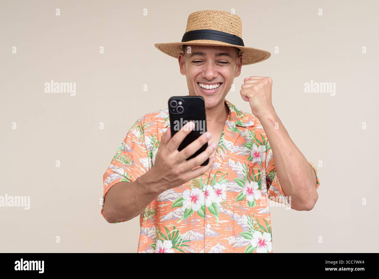 Glücklicher hispanischer Mann mit Panamahut und tropischem hawaiianischem Hemd, gekleidet in legere Sommermode. Der fröhliche Tourist posiert in entspanntem Urlaub Stockfoto