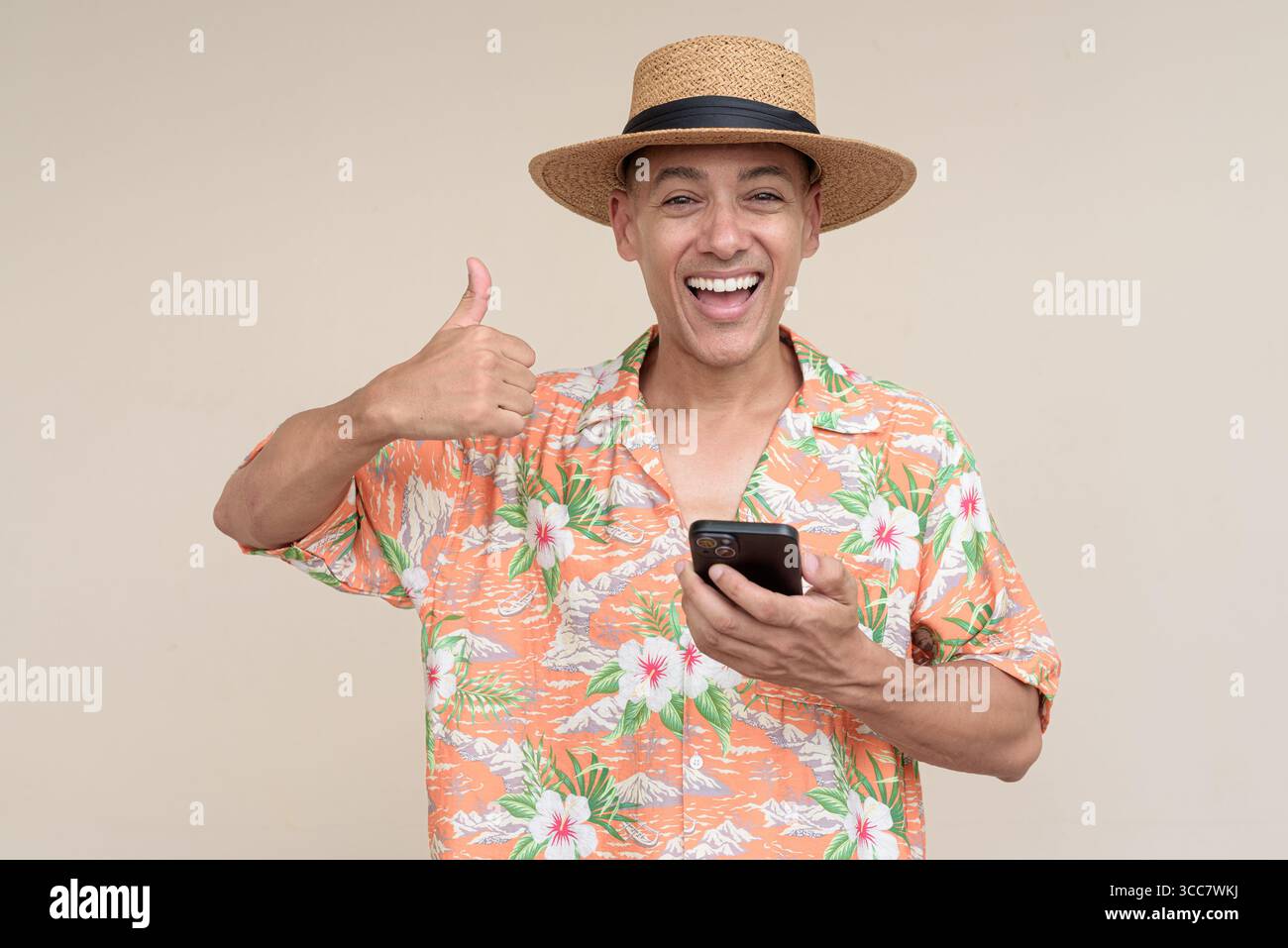 Glücklicher hispanischer Mann mit Panamahut und tropischem hawaiianischem Hemd, gekleidet in legere Sommermode. Der fröhliche Tourist posiert in entspanntem Urlaub Stockfoto
