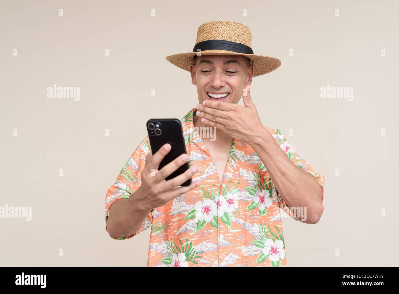 Glücklicher hispanischer Mann mit Panamahut und tropischem hawaiianischem Hemd, gekleidet in legere Sommermode. Der fröhliche Tourist posiert in entspanntem Urlaub Stockfoto