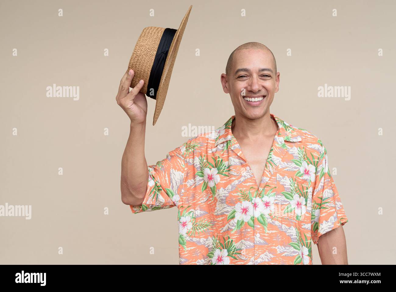 Glücklicher hispanischer Mann mit Panamahut und tropischem hawaiianischem Hemd, gekleidet in legere Sommermode. Der fröhliche Tourist posiert in entspanntem Urlaub Stockfoto