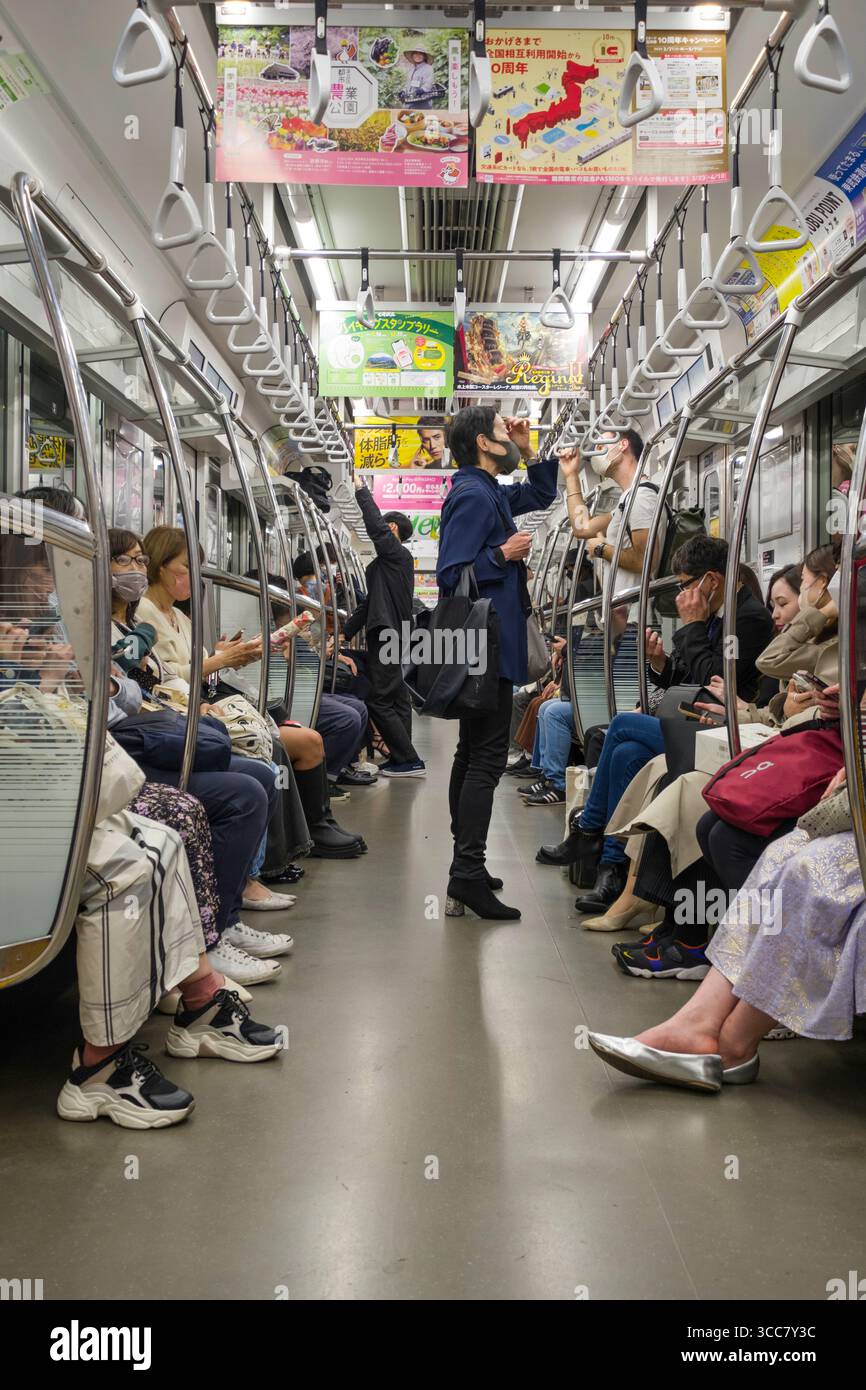 Personen sitzen und stehen im Tokyo Metro Hibiya Line Zug, Shibuya City, Tokio, Kantō, Honshu, Japan Stockfoto