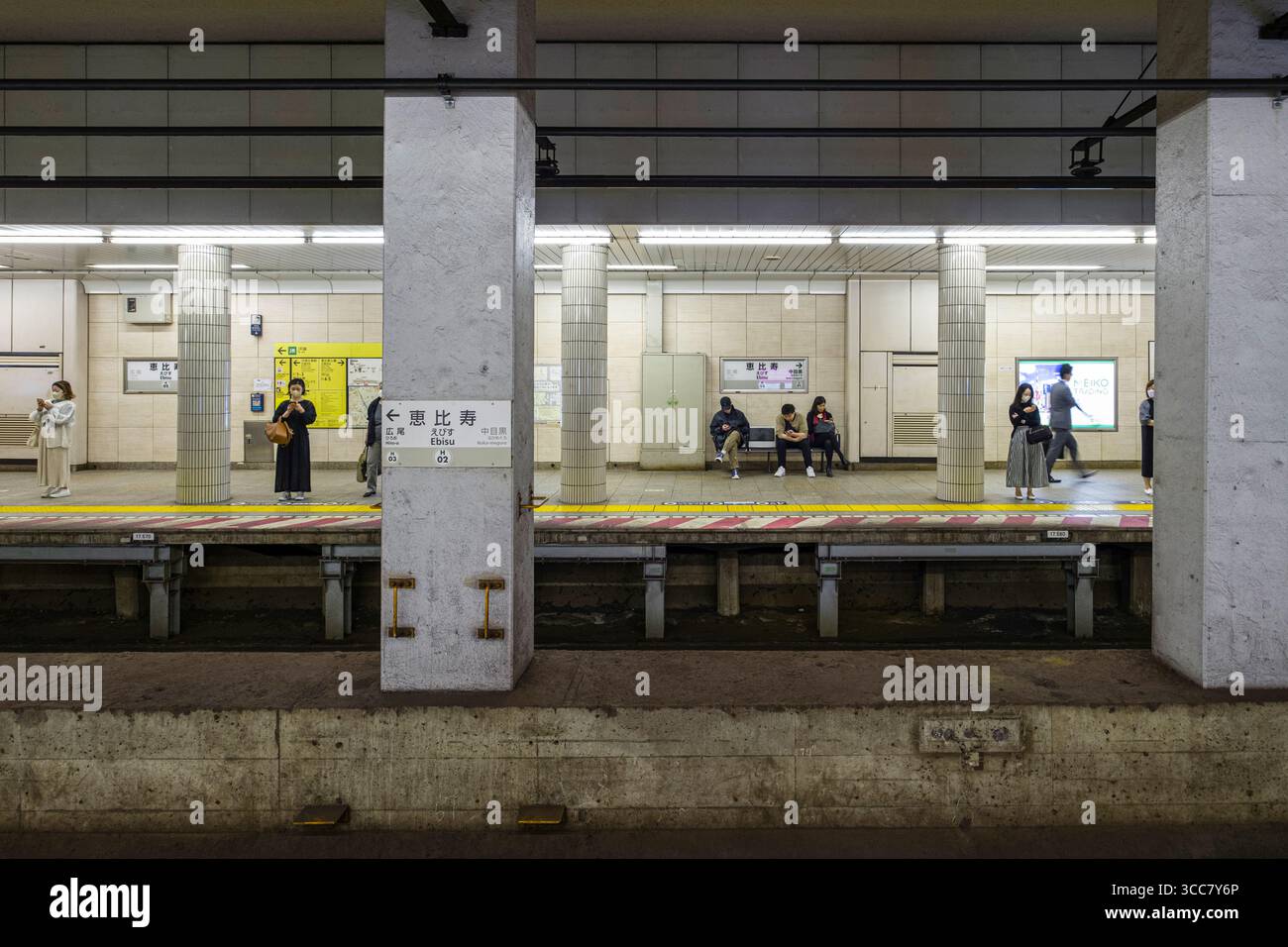 Personen sitzen und stehen in der Tokioter Metro Hibiya Line Ebisu Station, Ebisuminami, Shibuya City, Tokio, Kantō, Honshu, Japan Stockfoto