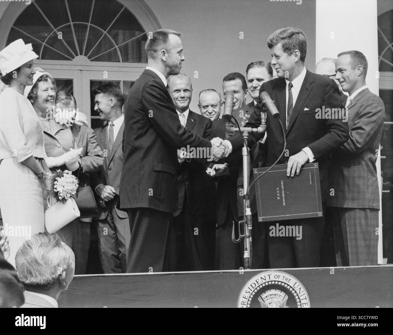 - Astronaut Alan B. Shepard Jr. erhält den NASA Distinguished Service Award vom US-Präsidenten John F. Kennedy am 8. Mai 1961, Tage nach seiner Geschichte, als er MR-3-Flug machte. Shepards Frau und Mutter links und die anderen sechs Mercury-Astronauten sind im Hintergrund. Stockfoto